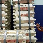 An employee checks tin ingots stacked in a warehouse