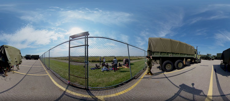 A distorted image of military vehicles in a parking lot next to a fence.