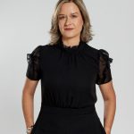 A woman stands with her hands in her pockets.