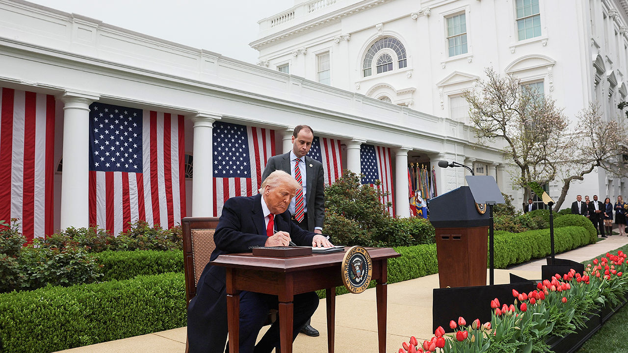 President Donald Trump signs an executive order on tariffs in the Rose Garden of the White House