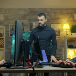 Three people working around computers and monitors