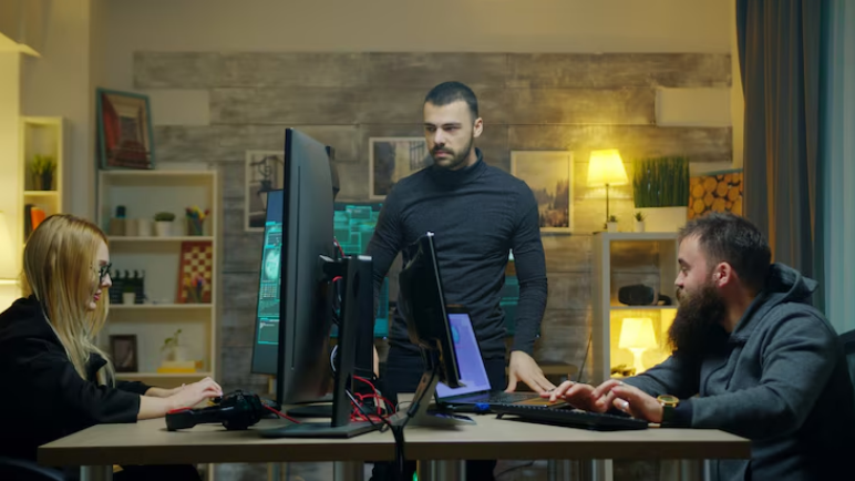 Three people working around computers and monitors