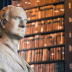 Photo of a bust of Isaac Newton in front of bookshelves at Trinity Library