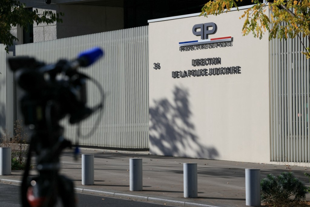 This photograph shows a journalist's camera pointed towards the headquarters of the Brigade de Repression du banditisme - BRB (Anti-organized crime squad) and the Direction Regionale de la Police Judiciaire de Paris (Paris Judicial Police) after two suspects were arrested as part of the investigation into the Louvre robbery, in Paris on October 26, 2025. A week after the spectacular theft of eight French crown jewels in a matter of minutes from the Louvre Museum, two men suspected of being part of the gang were arrested and taken into custody. In a statement on October 26, 2025, the Paris prosecutor confirmed "that investigators from the Brigade de Repression du banditisme - BRB (Anti-organized crime squad) had carried out arrests in the evening of October 25, 2025". (Photo by Alain JOCARD / AFP)